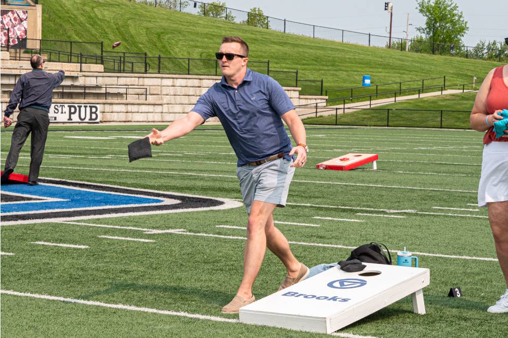 Man determinedly tosses a cornhole bag to the board opposite of him